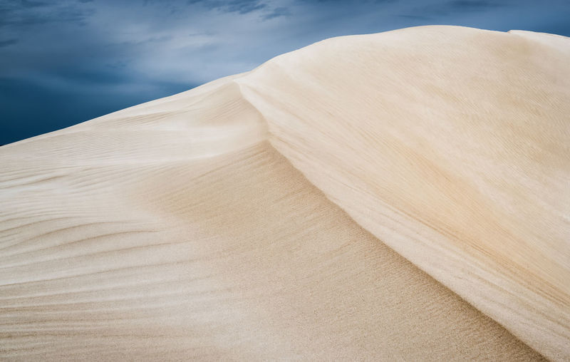 Close-up of sand dune in desert against sky