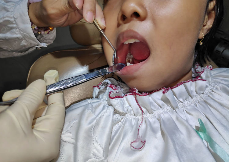 Cropped hands of dentist examining girl