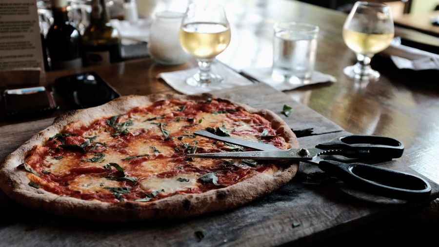 Close-up of pizza and scissor on table