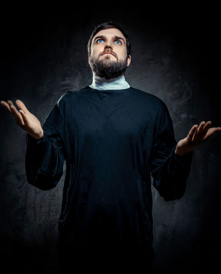 Priest standing against black background