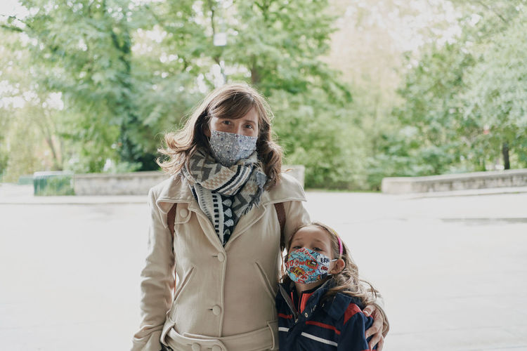 Mather and daughter wearing a white coat and a medical mask obse