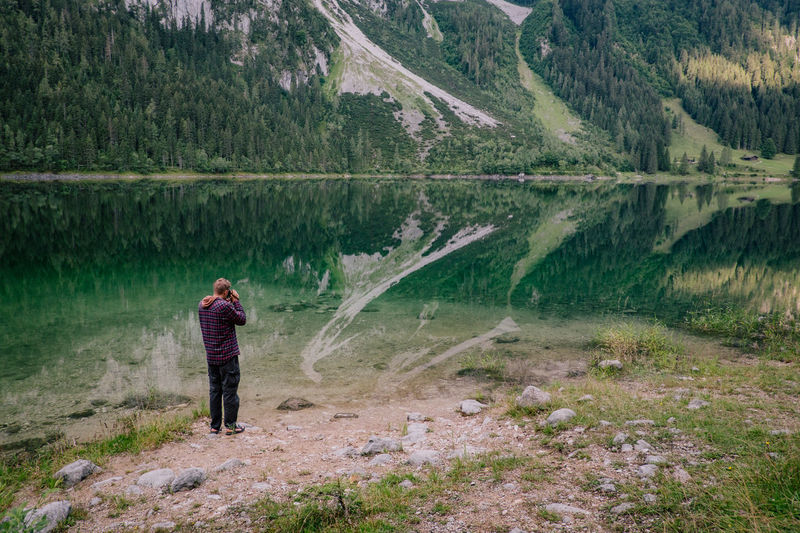 Man standing against lake and mountains