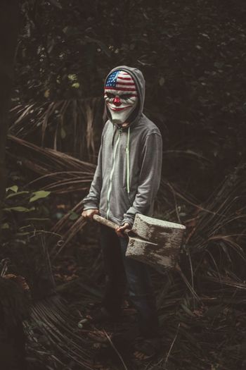 Man in mask holding spade in forest