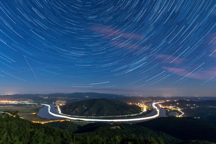 Light trails on mountain against sky at night