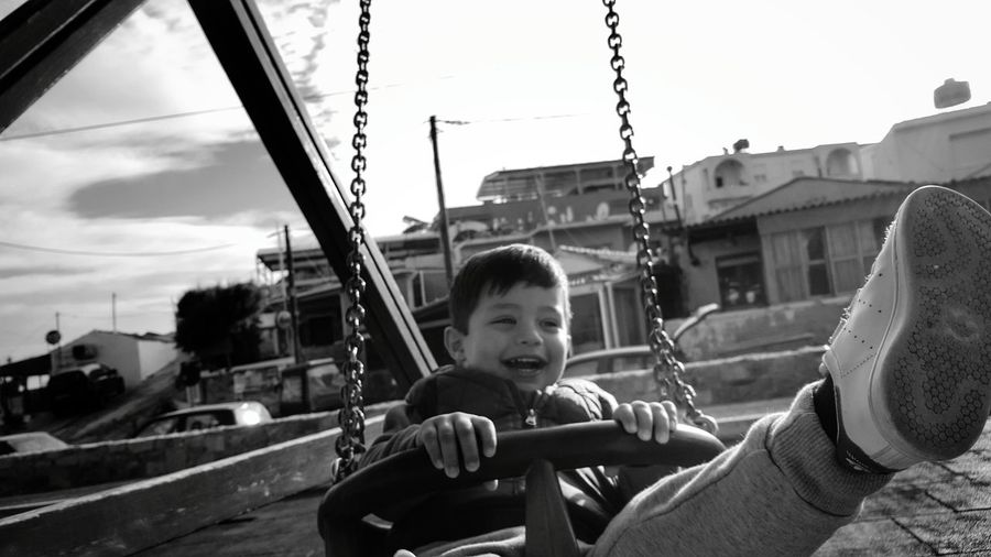 Boy enjoying while sitting in chain swing