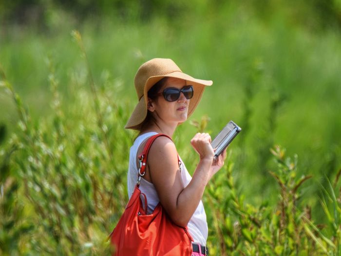 Woman using digital tablet while standing on field 
