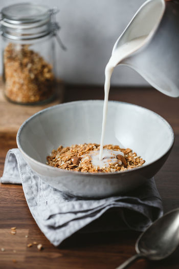 Close-up of milk pouring in breakfast cereal on table