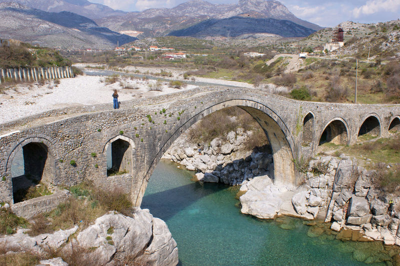 Arch bridge over river against mountains