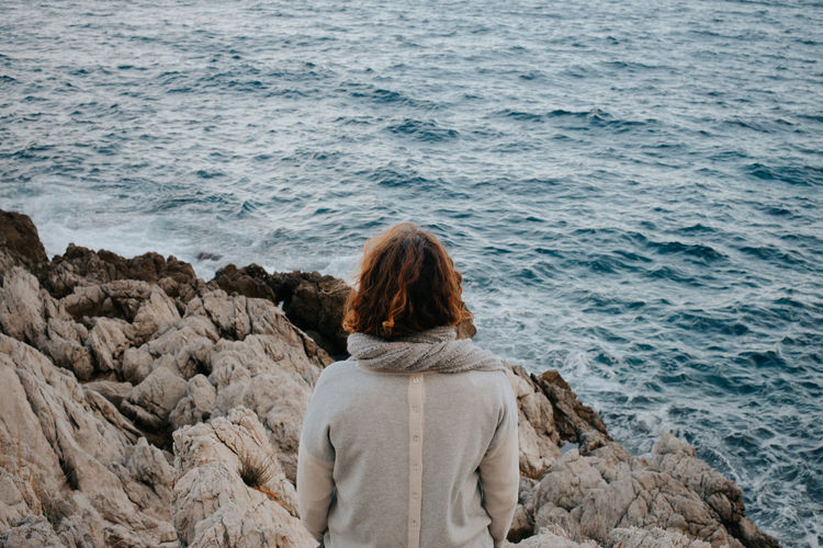 Rear view of woman looking at sea on rocks