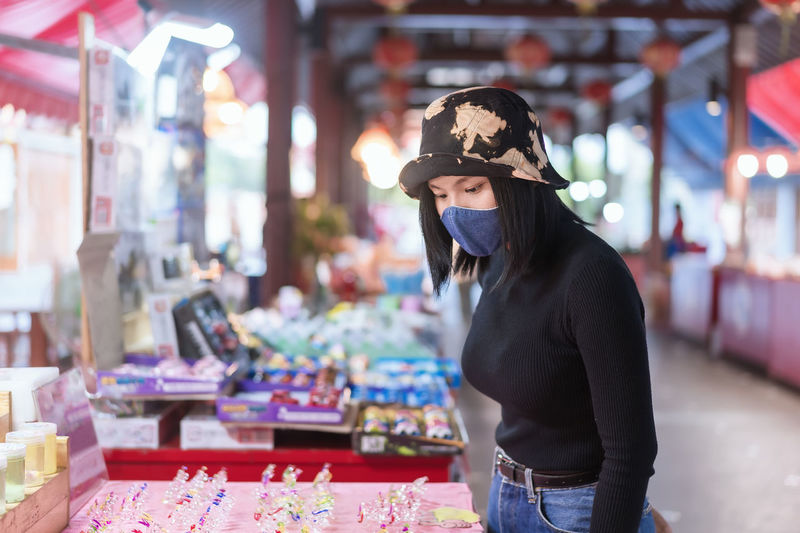 Portrait of happy young tourist woman wearing a protective mask in shopping during coronavirus