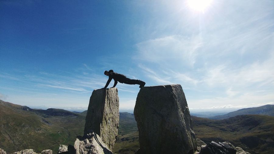 Man exercising on rock formations against sky