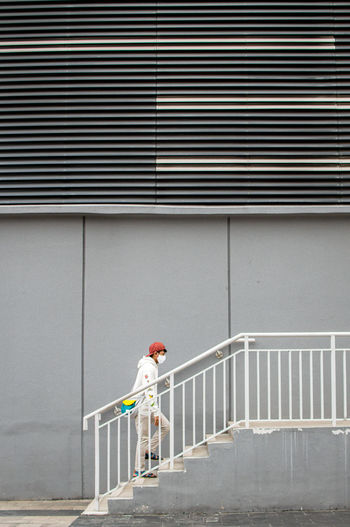 Man wearing mask walking on staircase of building