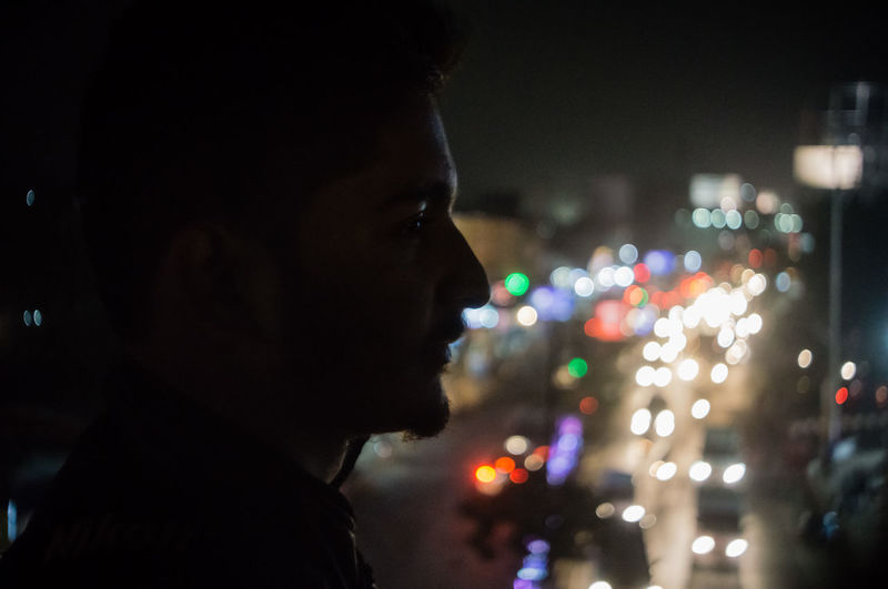 Close-up of man in illuminated city