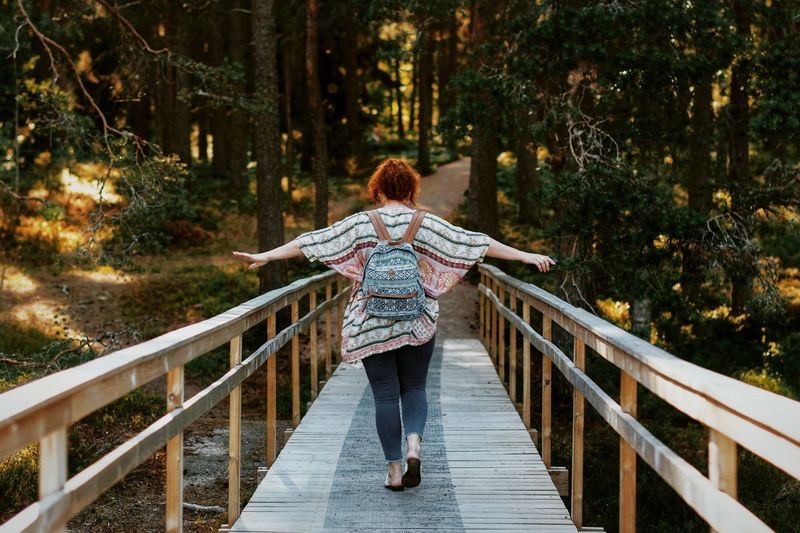 Rear view of woman on footbridge in forest