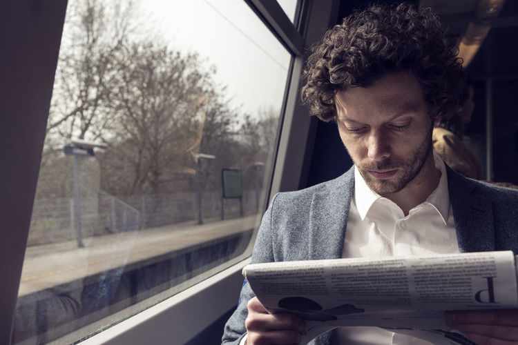 Businessman reading newspaper in train