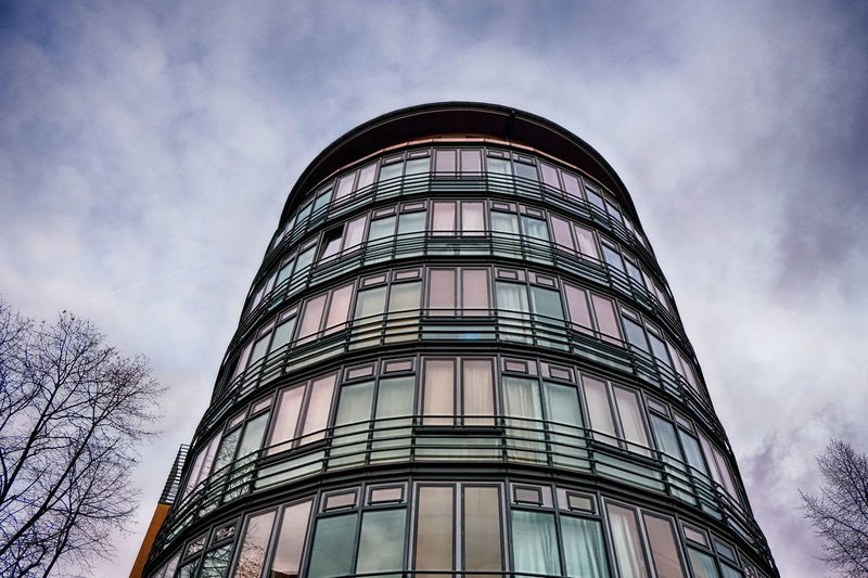 Low angle view of modern building against cloudy sky