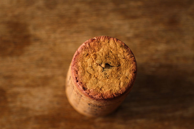 Macro photo of cork stopper seen from above, out of focus wooden table background.