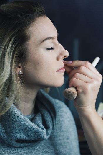 Cropped hands applying make-up to woman