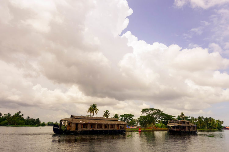 Boathouses in backwaters against cloudy sky