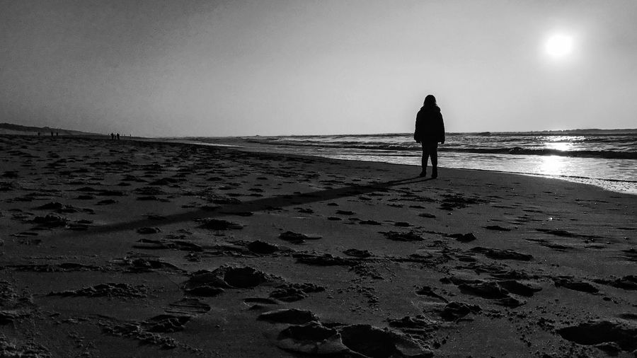 Rear view of silhouette woman walking on beach
