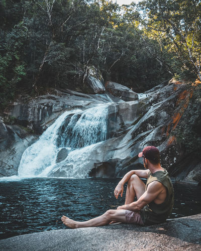 Man sitting on rock looking at waterfalls