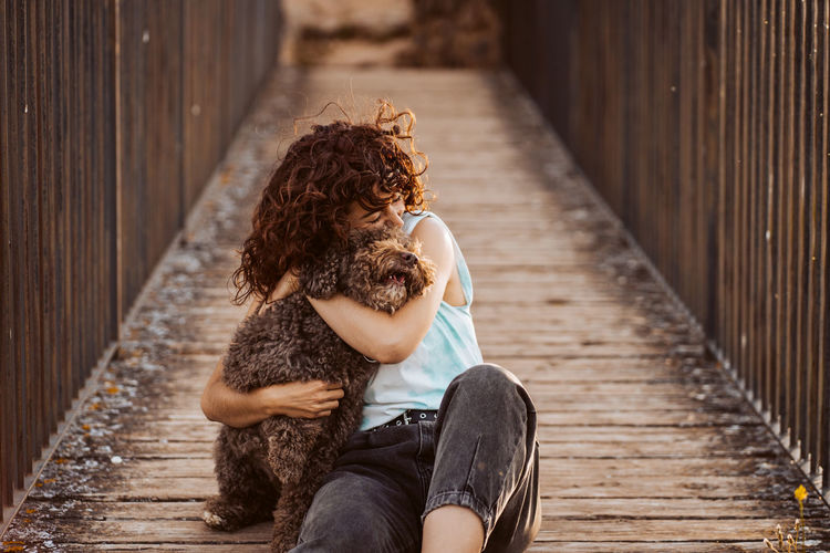 Woman embracing dog on boardwalk