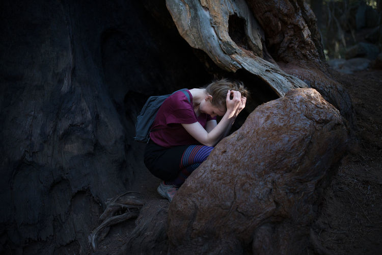 Tensed woman crouching on rock