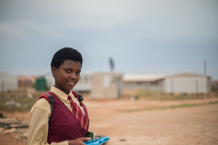 Portrait of smiling girl in school uniform against sky