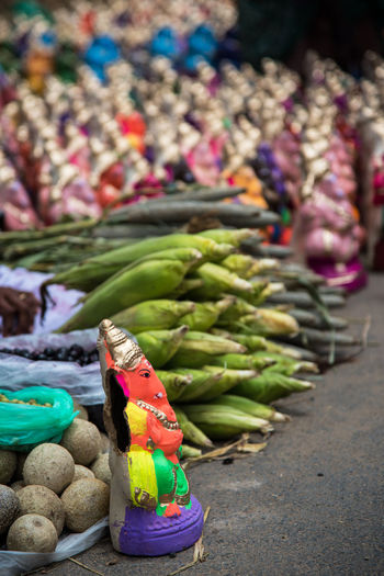 Close-up of ganesha statues by vegetables for sale in market
