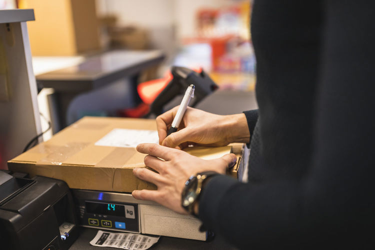 Male store owner writing on package at checkout