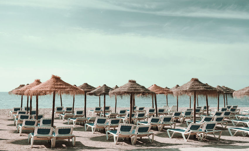 Lounge chairs on beach against sky