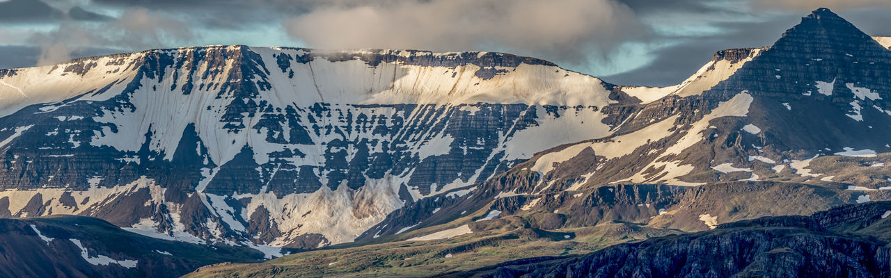Rugged mountain range dominates panoramic scenery during a brief icelandic summer