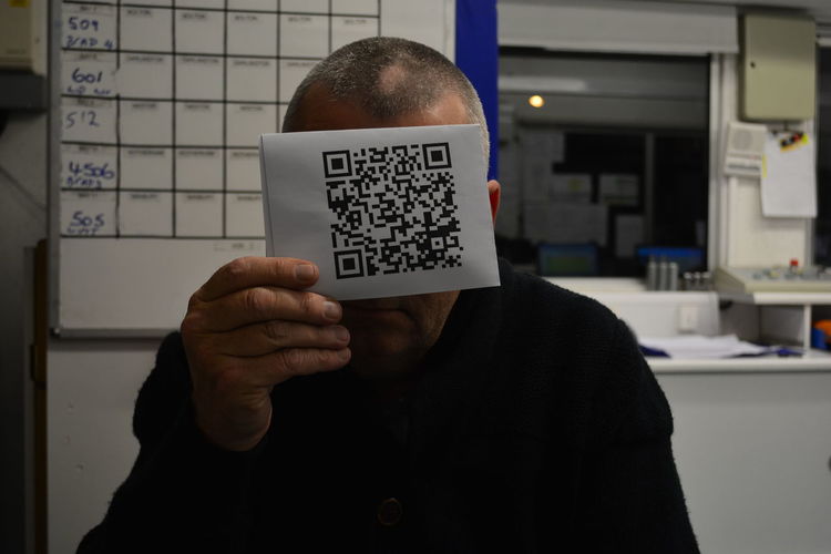 Close-up of man holding qr code at office