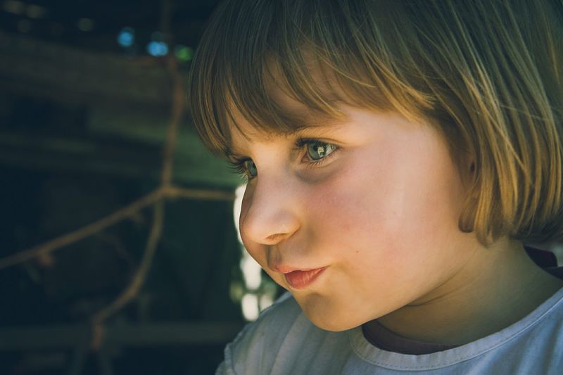 Close-up of cute girl with short blond hair looking away