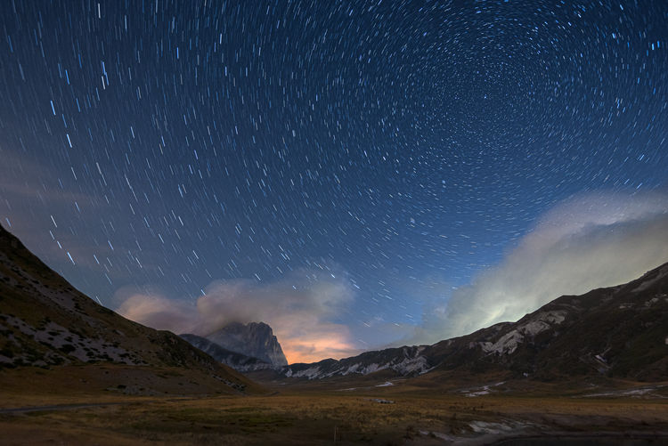 Scenic view of mountains against sky at night, campo imperatore