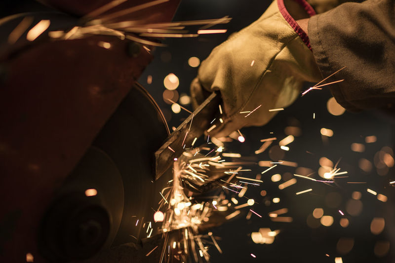 Metal worker using grinding machine in factory workshop