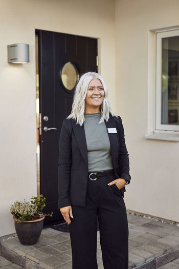 Smiling estate agent standing in front of house