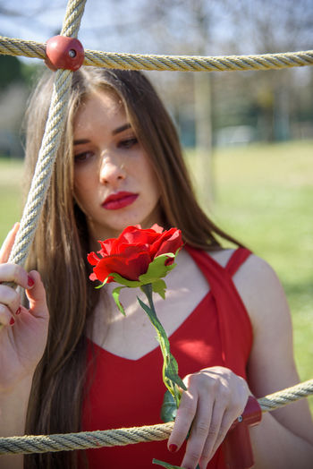 Portrait of beautiful woman holding red flowering plant