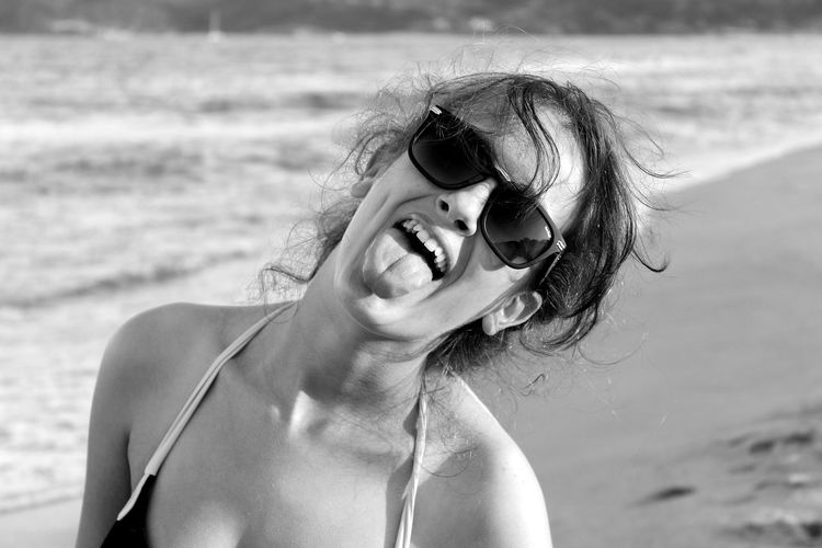 Portrait of playful woman making face at beach