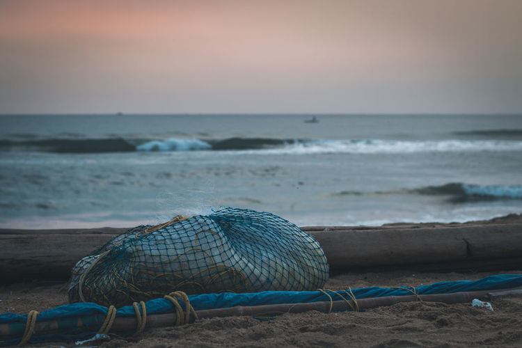 Close-up of fishing net at beach against sky
