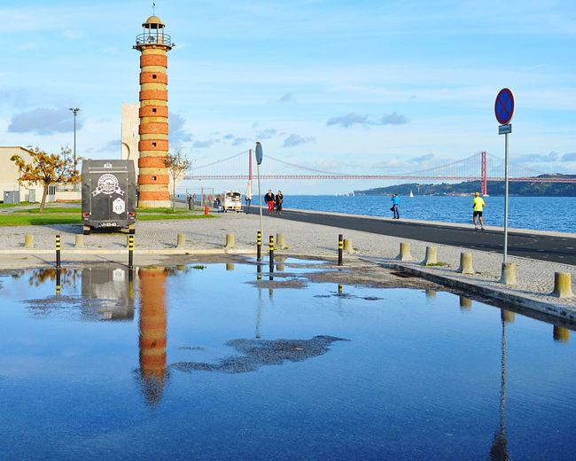 Reflection of lighthouse on sea against sky