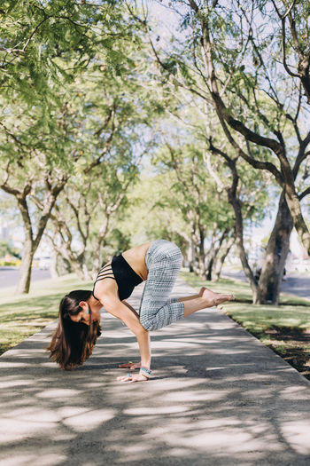 Woman of mexican ethnicity and middle age 35-39 years old doing a crow yoga pose in a park in wuete