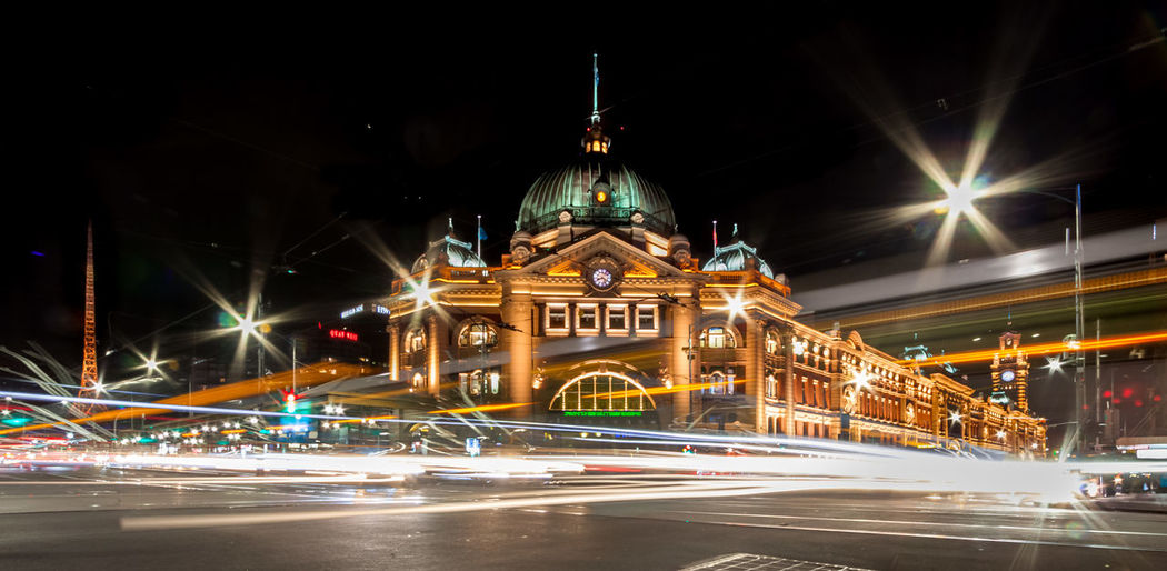 Flinders street station with light trails on road at night
