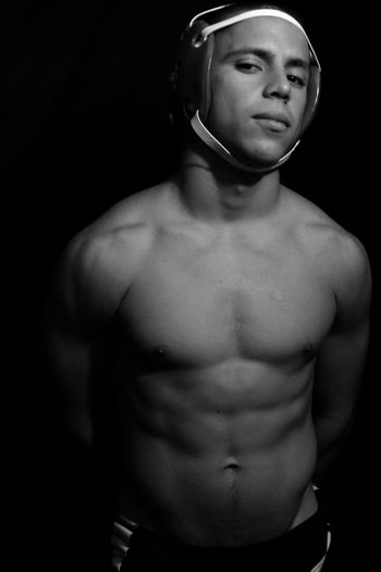 Portrait of confident shirtless wrestler against black background