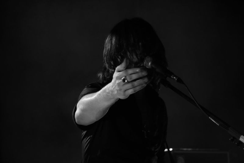 Man singing while gesturing against black background