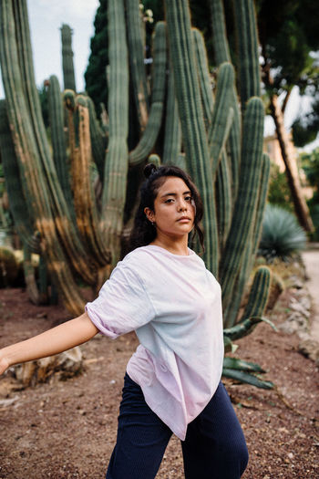 Latina girl with boho shirt dancing surrounded by cactus'
