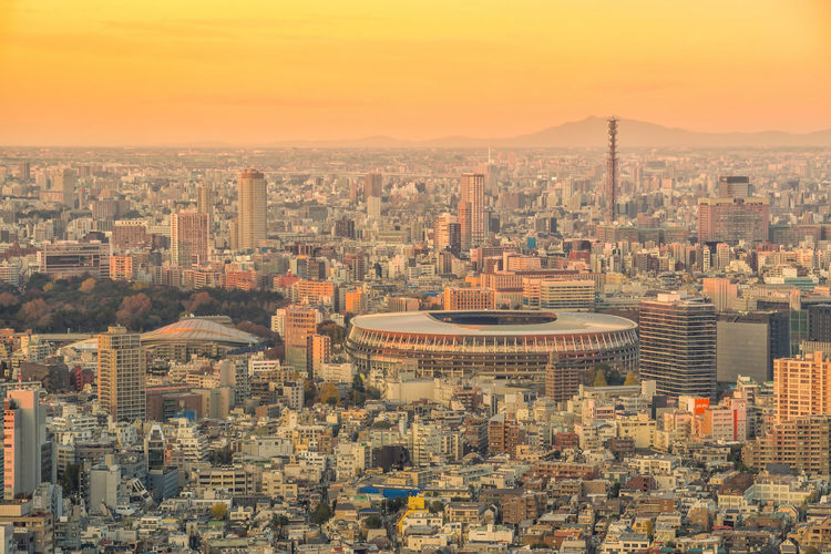 Aerial view of modern buildings in city against sky during sunset