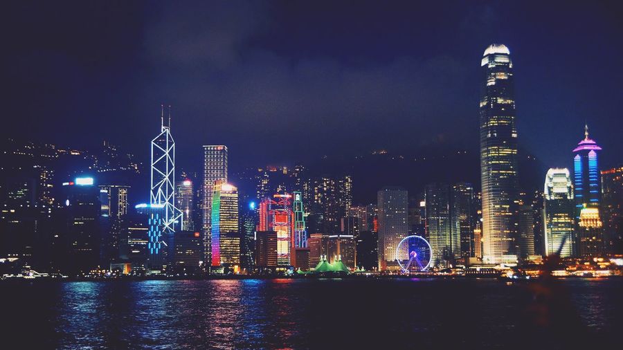 Illuminated buildings by victoria harbour at night
