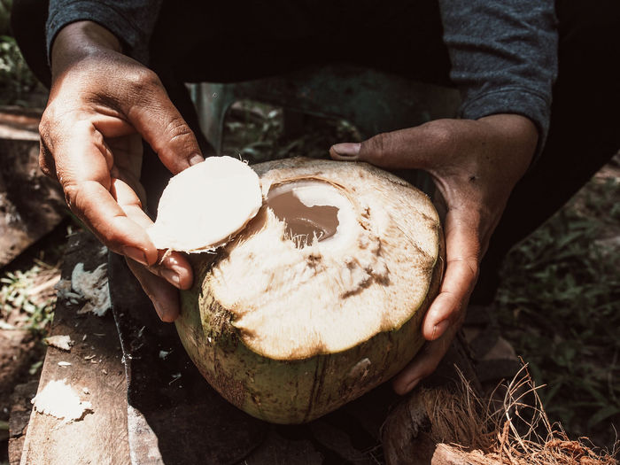 Asian farmer peeling a fresh coconut