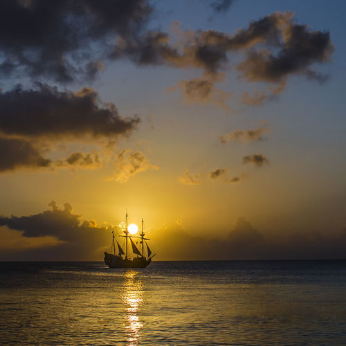 Silhouette ship sailing on sea against sky during sunset